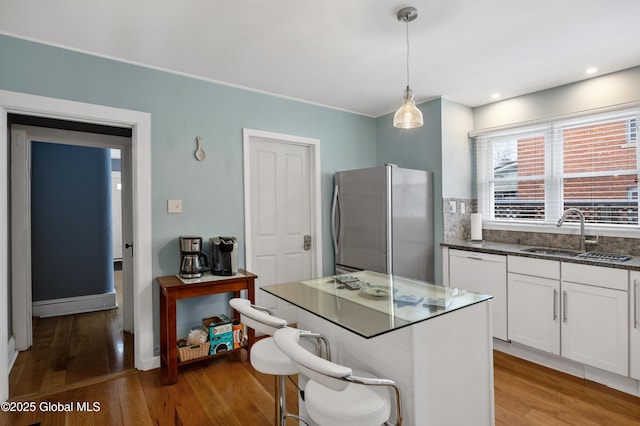 kitchen with white cabinets, dishwasher, sink, hanging light fixtures, and stainless steel fridge