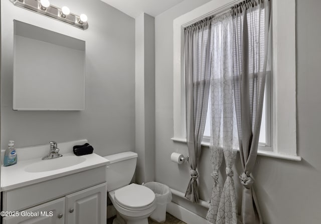 bathroom featuring toilet, vanity, and a wealth of natural light