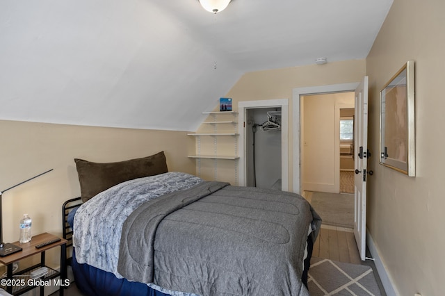 bedroom featuring lofted ceiling, a walk in closet, a closet, and light hardwood / wood-style floors