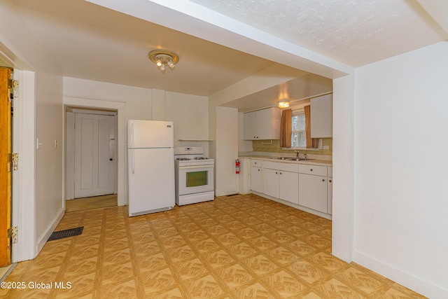 kitchen with white appliances, white cabinets, decorative backsplash, and sink