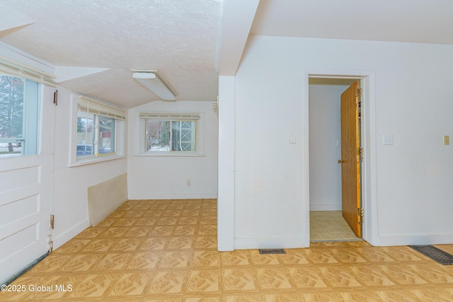 spare room with a textured ceiling and lofted ceiling