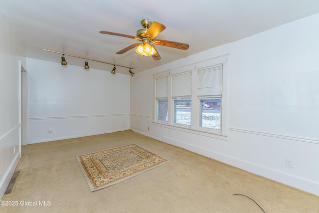 empty room featuring ceiling fan, track lighting, and light carpet