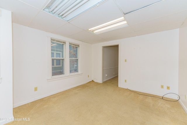 empty room featuring a paneled ceiling and light carpet