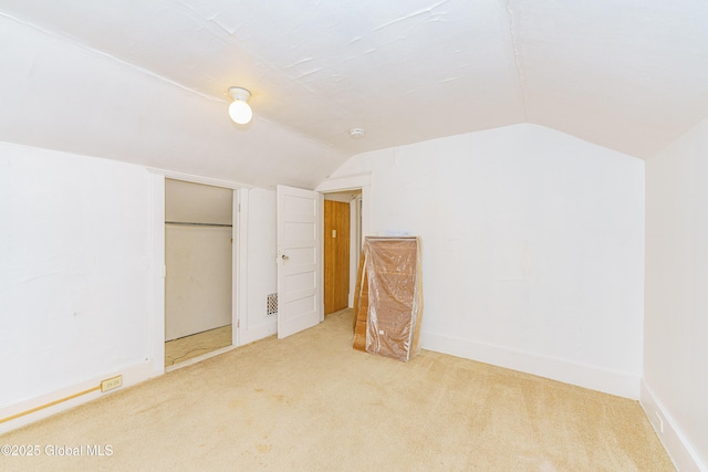 unfurnished bedroom with lofted ceiling, carpet flooring, and a closet