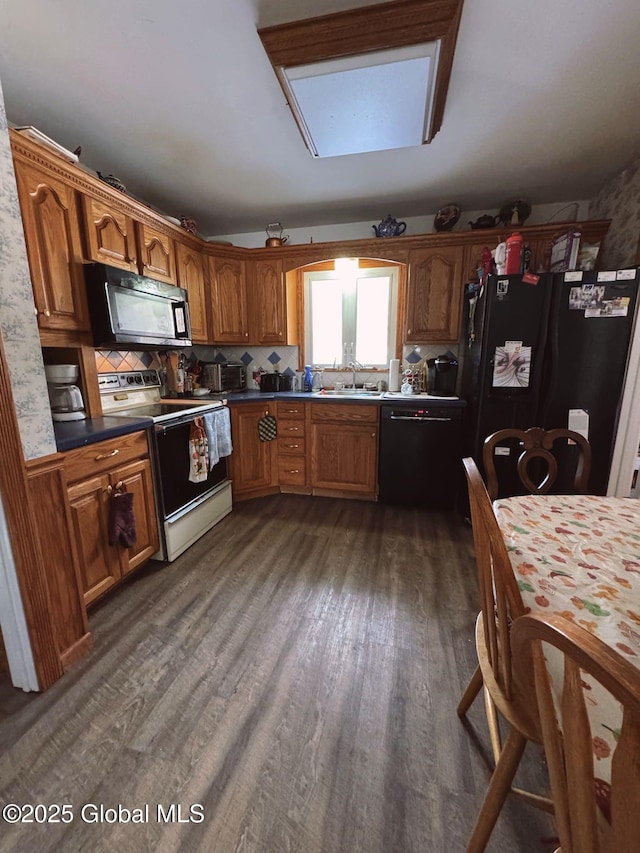 kitchen featuring black appliances, dark hardwood / wood-style flooring, sink, and tasteful backsplash