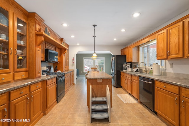 kitchen with black appliances, sink, hanging light fixtures, and a kitchen island