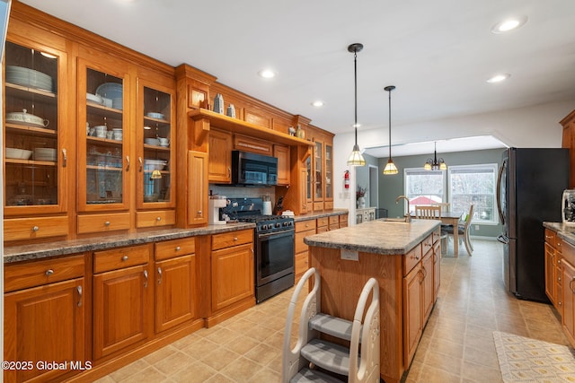 kitchen featuring decorative light fixtures, sink, a kitchen island with sink, stainless steel refrigerator, and gas range