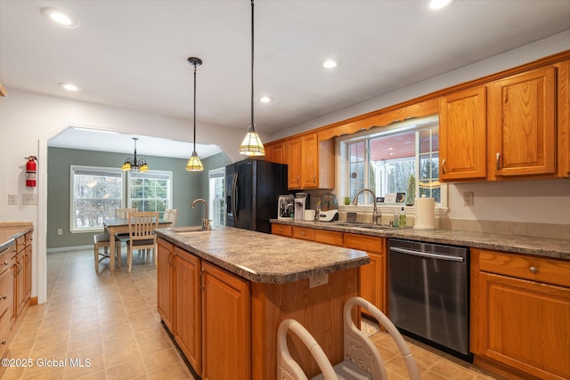 kitchen with stainless steel dishwasher, black refrigerator with ice dispenser, sink, and a center island with sink