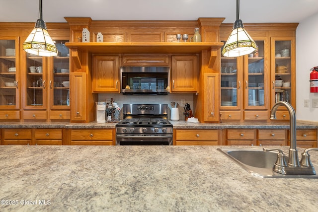 kitchen with decorative backsplash, sink, hanging light fixtures, and gas stove