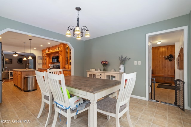 dining room with ceiling fan with notable chandelier and sink