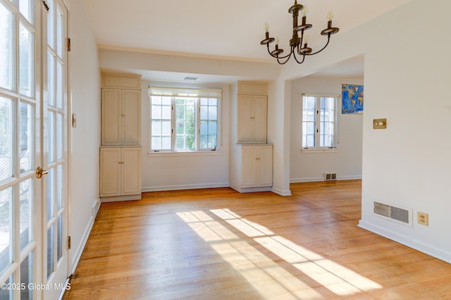 unfurnished dining area featuring light hardwood / wood-style floors and an inviting chandelier