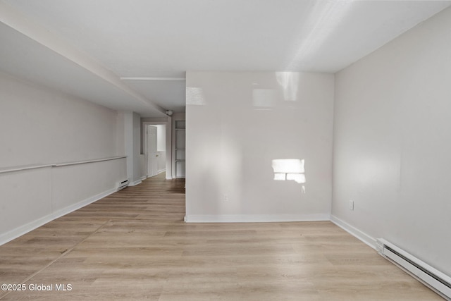 unfurnished room with baseboard heating and light hardwood / wood-style flooring