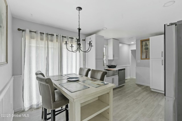 dining space featuring light wood-type flooring, sink, and a chandelier