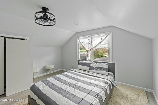 bedroom with light wood-type flooring and vaulted ceiling