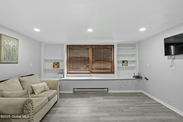 living room featuring built in shelves, light wood-type flooring, and a baseboard radiator