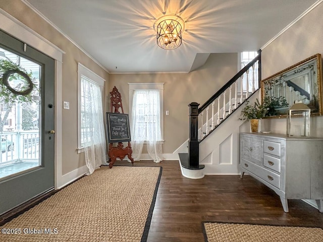 entrance foyer with dark wood-type flooring, an inviting chandelier, and crown molding