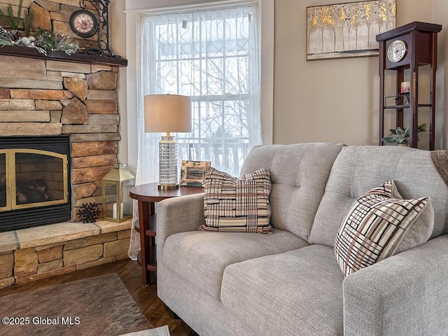 sitting room featuring dark wood-type flooring and a stone fireplace