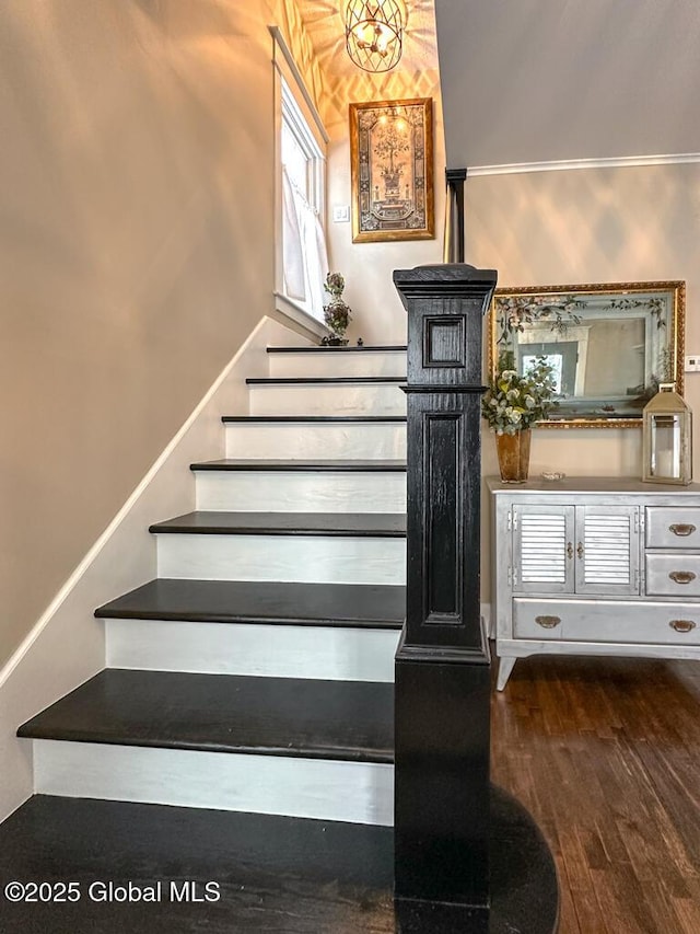 stairway featuring wood-type flooring and an inviting chandelier