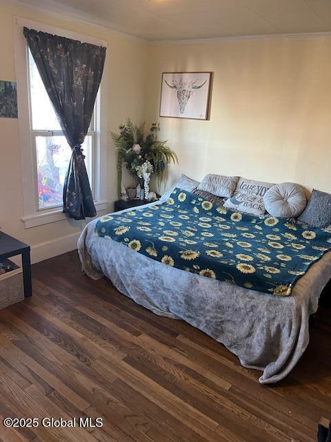 bedroom with ornamental molding and dark wood-type flooring