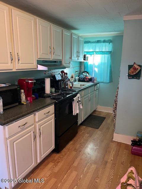 kitchen with white cabinets, light hardwood / wood-style flooring, black electric range, and sink