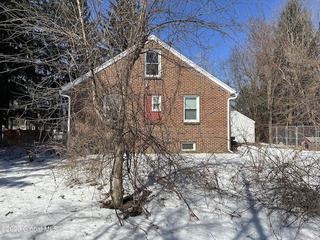 view of snowy exterior with brick siding