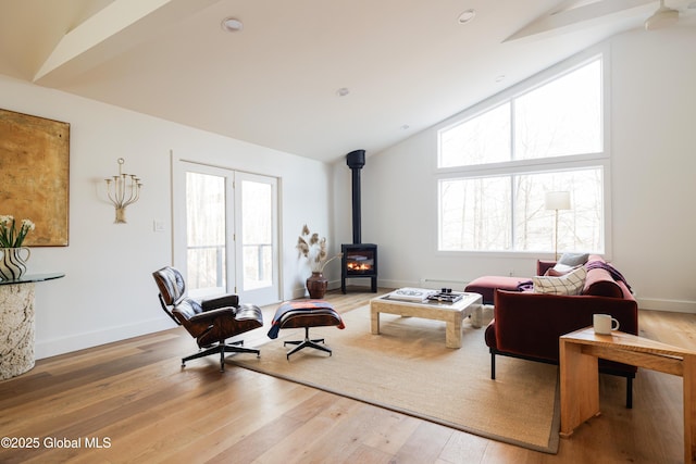 living room with lofted ceiling with beams, a wood stove, and wood-type flooring