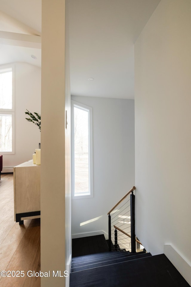 stairs with hardwood / wood-style floors, vaulted ceiling, and a baseboard heating unit