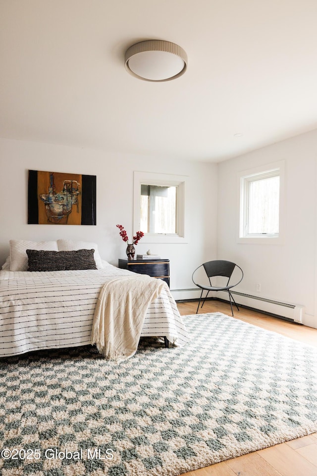 bedroom featuring baseboard heating and hardwood / wood-style flooring