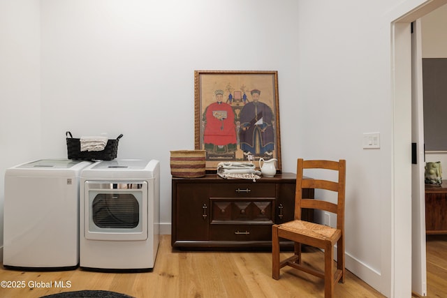 clothes washing area with separate washer and dryer and light hardwood / wood-style floors