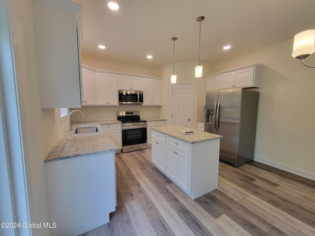 kitchen with a center island, sink, stainless steel appliances, decorative light fixtures, and white cabinets