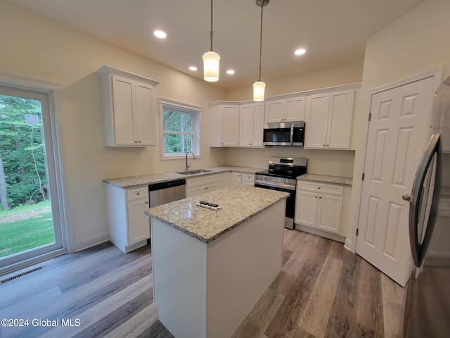 kitchen featuring appliances with stainless steel finishes, sink, pendant lighting, a center island, and white cabinetry