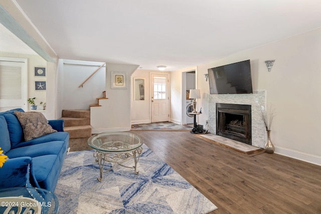 living area with stairs, wood finished floors, baseboards, and a fireplace