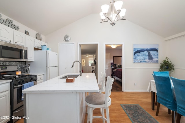 kitchen featuring light wood-type flooring, a breakfast bar, a sink, appliances with stainless steel finishes, and lofted ceiling