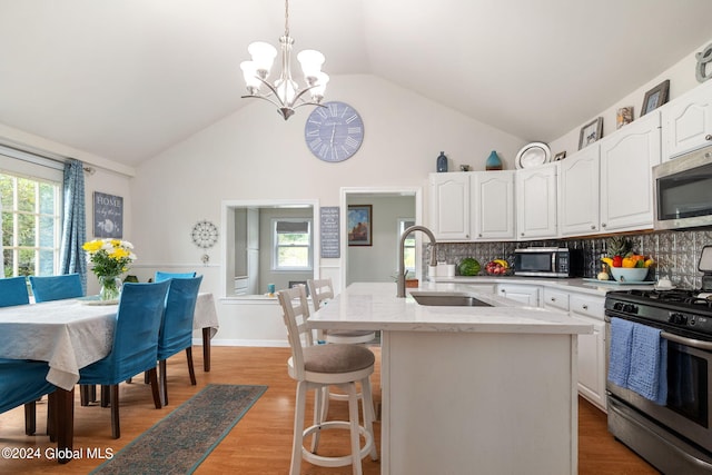 kitchen with light stone counters, white cabinets, appliances with stainless steel finishes, and a sink