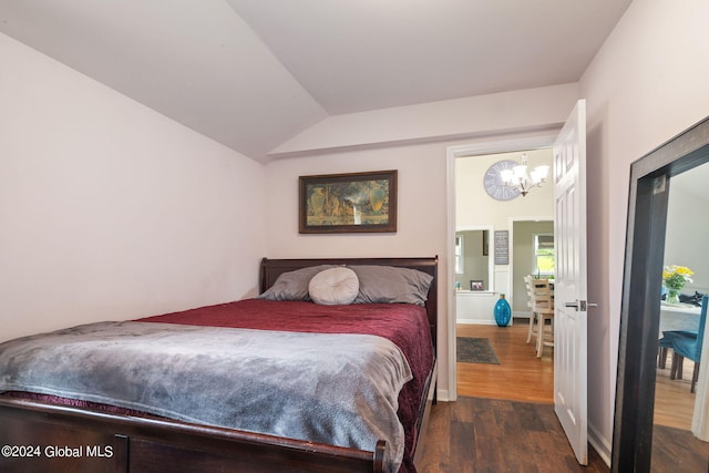 bedroom with vaulted ceiling, an inviting chandelier, and wood finished floors