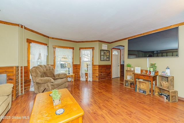 living room with crown molding, wood walls, and hardwood / wood-style flooring