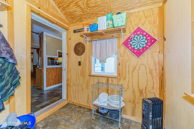 misc room featuring lofted ceiling, wood walls, and heating unit