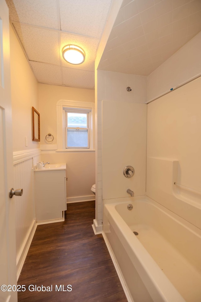 full bathroom featuring toilet, bathtub / shower combination, a paneled ceiling, hardwood / wood-style floors, and vanity