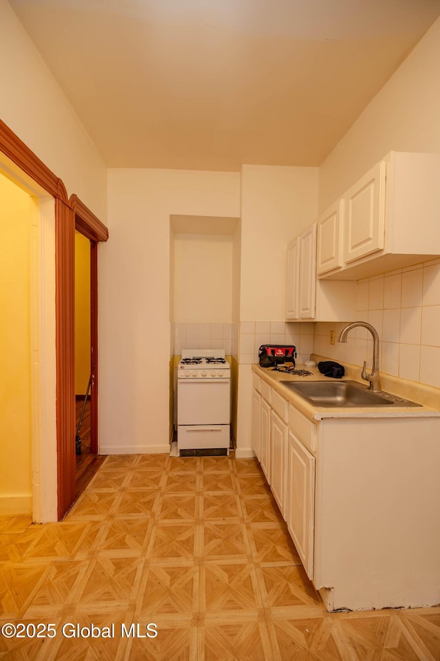 kitchen with sink, white cabinets, light parquet flooring, white range with gas cooktop, and backsplash