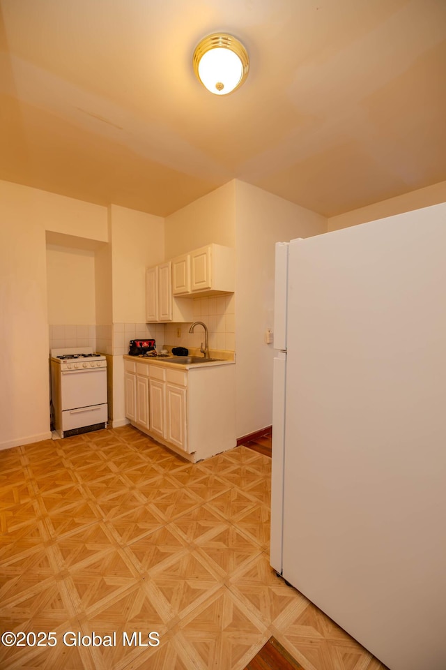 kitchen featuring sink, white cabinets, light parquet floors, white appliances, and decorative backsplash