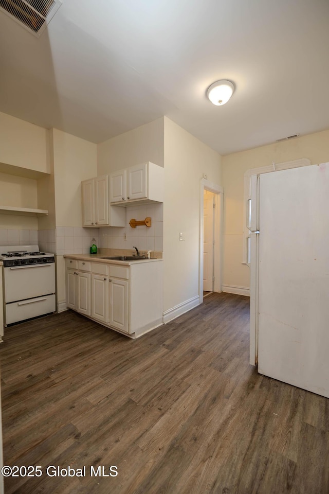 kitchen with sink, dark hardwood / wood-style flooring, white appliances, and backsplash