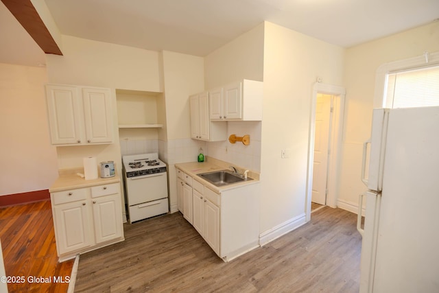 kitchen with white appliances, white cabinets, wood-type flooring, and sink