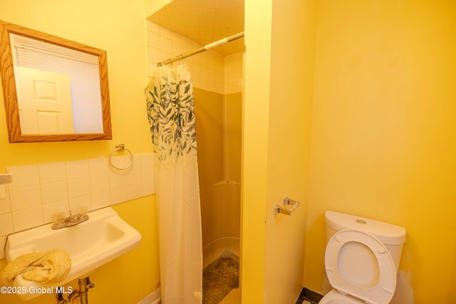 bathroom featuring curtained shower, toilet, sink, and backsplash