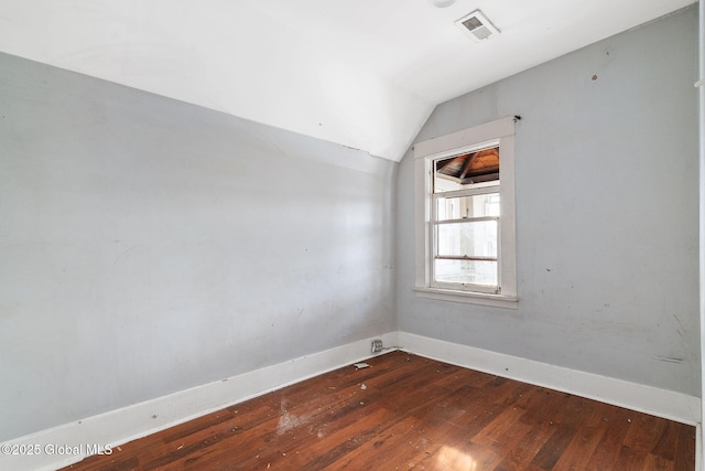 spare room featuring dark hardwood / wood-style flooring and lofted ceiling