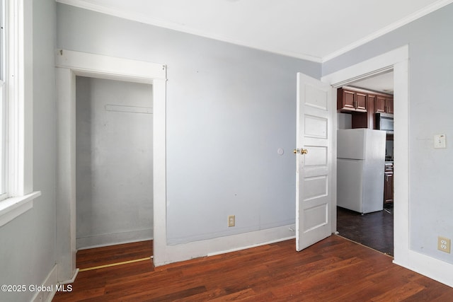 unfurnished bedroom with dark wood-type flooring, ornamental molding, a closet, and white refrigerator