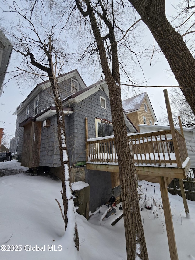 snow covered back of property featuring a deck