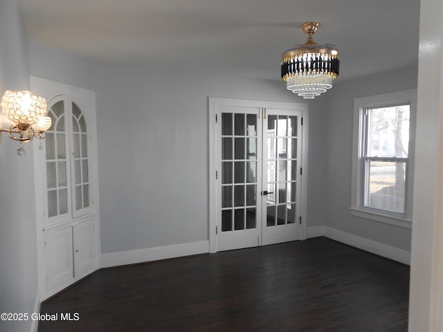 unfurnished dining area with french doors, dark hardwood / wood-style flooring, and an inviting chandelier