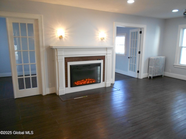 unfurnished living room featuring dark hardwood / wood-style flooring, french doors, and radiator