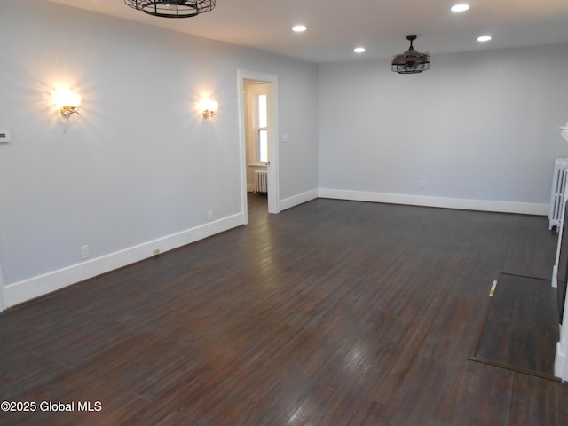 spare room featuring dark hardwood / wood-style floors and radiator