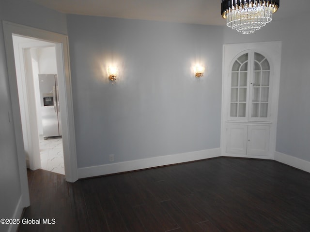 unfurnished room with dark wood-type flooring and a chandelier